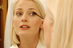 Woman putting on mascara in bathroom mirror 1.jpg