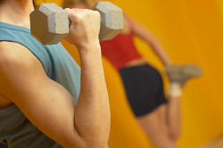 Mature adult woman lifting weights with woman stretching in background uid 1427320.jpg